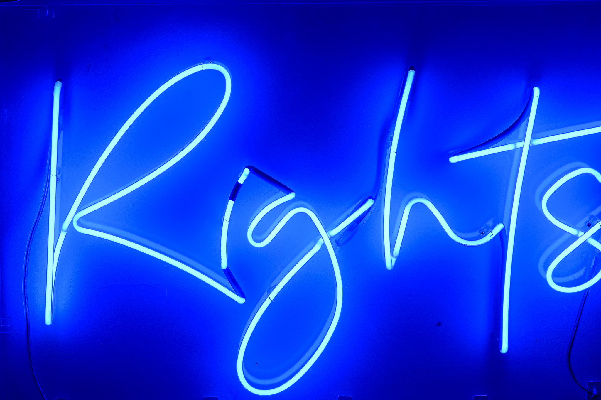 A close up of the word 'Rights' in blue marine neon lights in a stylised handwritten font