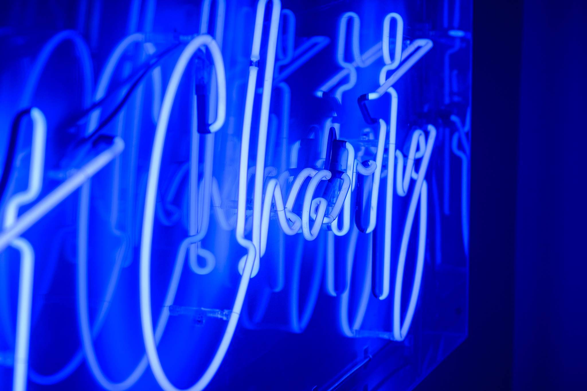 A close up of the word 'Charity' in blue marine neon lights in a stylised handwritten font