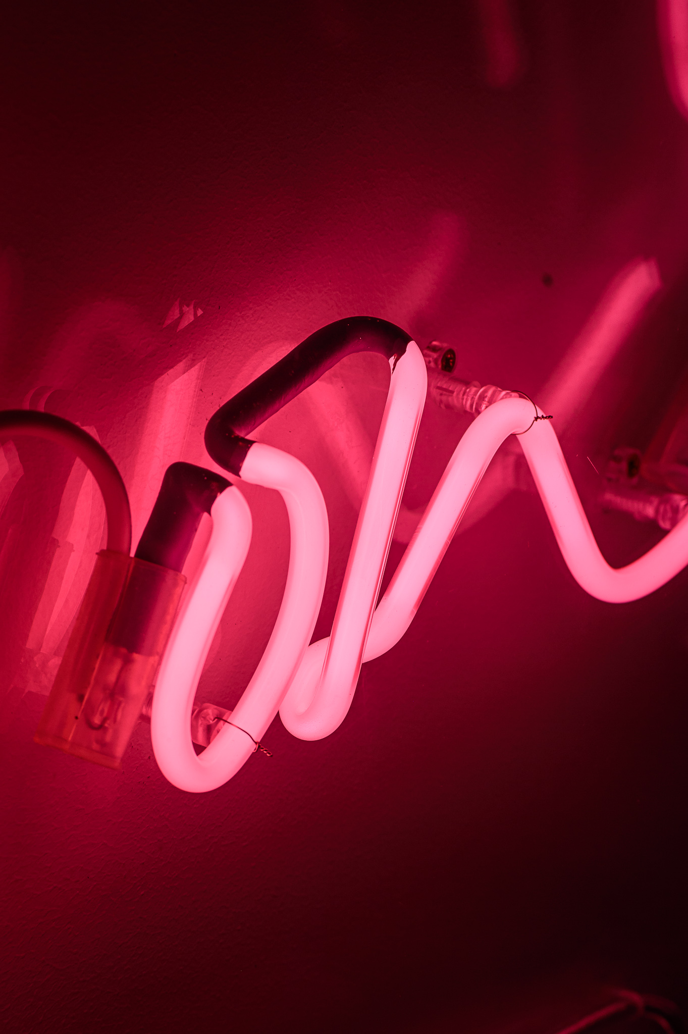 Close up photo on the word 'on' in bright pink neon lights quite flamboyant in a stylised handwritten font. The neon words are framed inside a transparent Perspex box. 